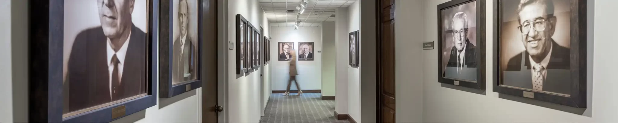 A corridor with multiple framed pictures hanging on the wall