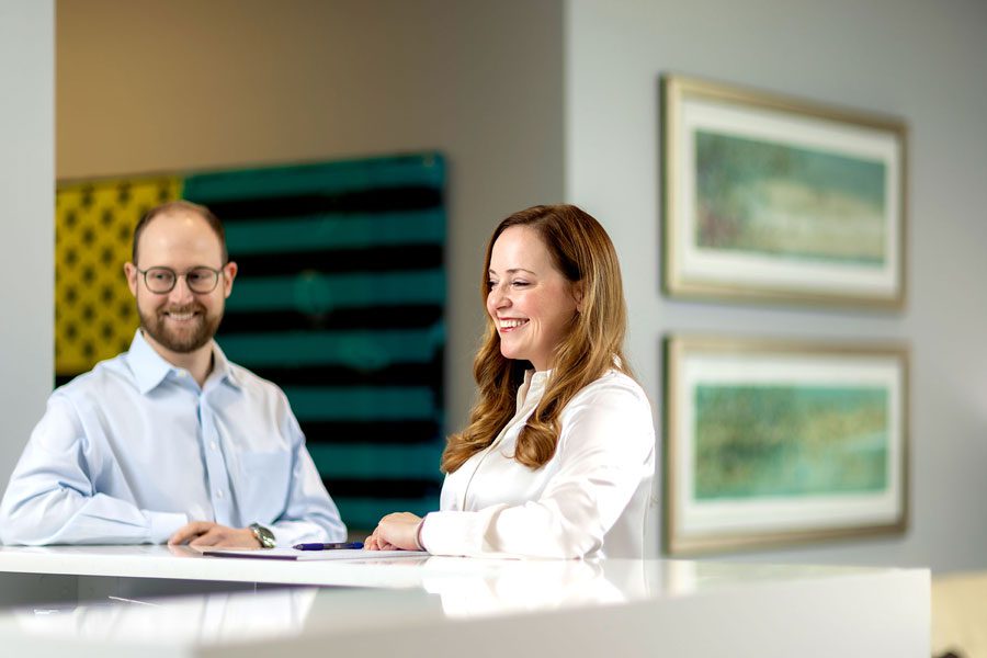 Man and woman sitting behind a desk and smiling